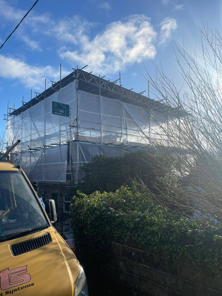 a building with scaffolding and a van parked in front of it
