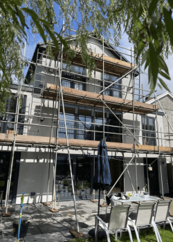 Three story modern home covered in scaffolding